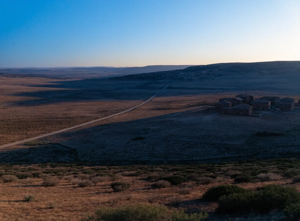 Meseta interior española al atardecer, con campos extensos y construcciones dispersas